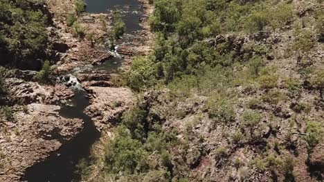 drone footage over large lake in kakadu national park flying towards multiple waterfalls