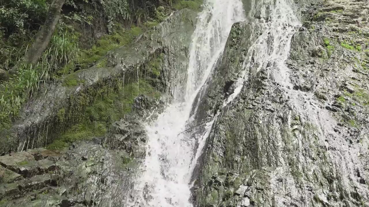 Vann spruter over teksturert stein ved Yeddi Gozel-fossen i Gabala i et nærbilde i dagslys