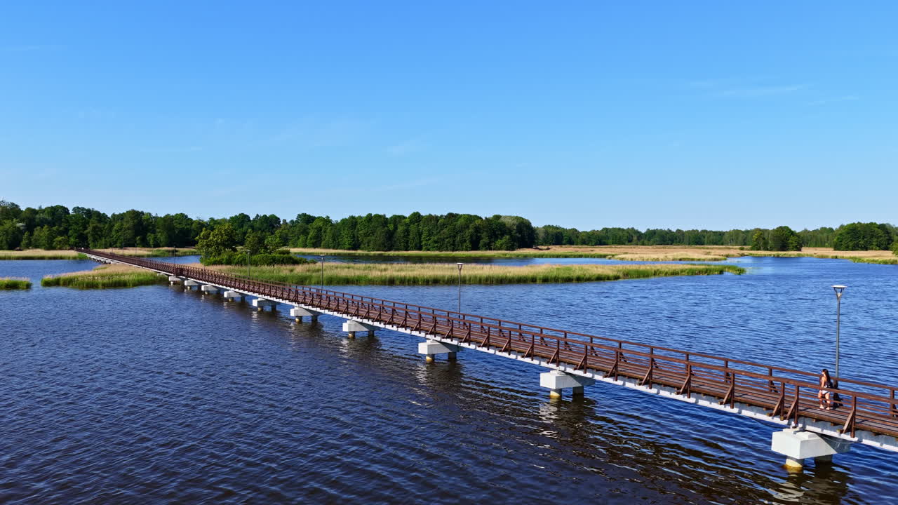 Woman crossing sirvėnos ezero tiltas bridge in lake Sirvena, Slovenia. Aerial