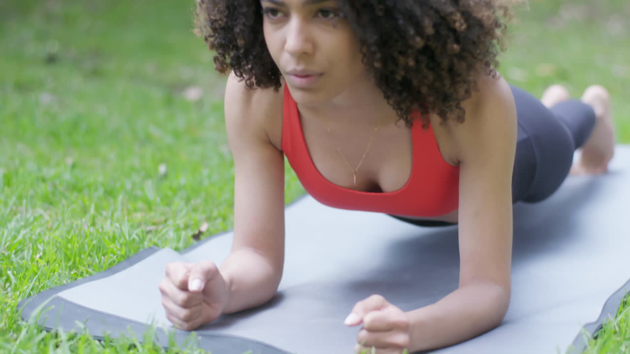 mujer en forma realiza con gracia la postura de la tabla durante una sesión de yoga al aire libre en un jardín, conectándose con la naturaleza y su ser interior a través de movimientos enfocados y equilibrados