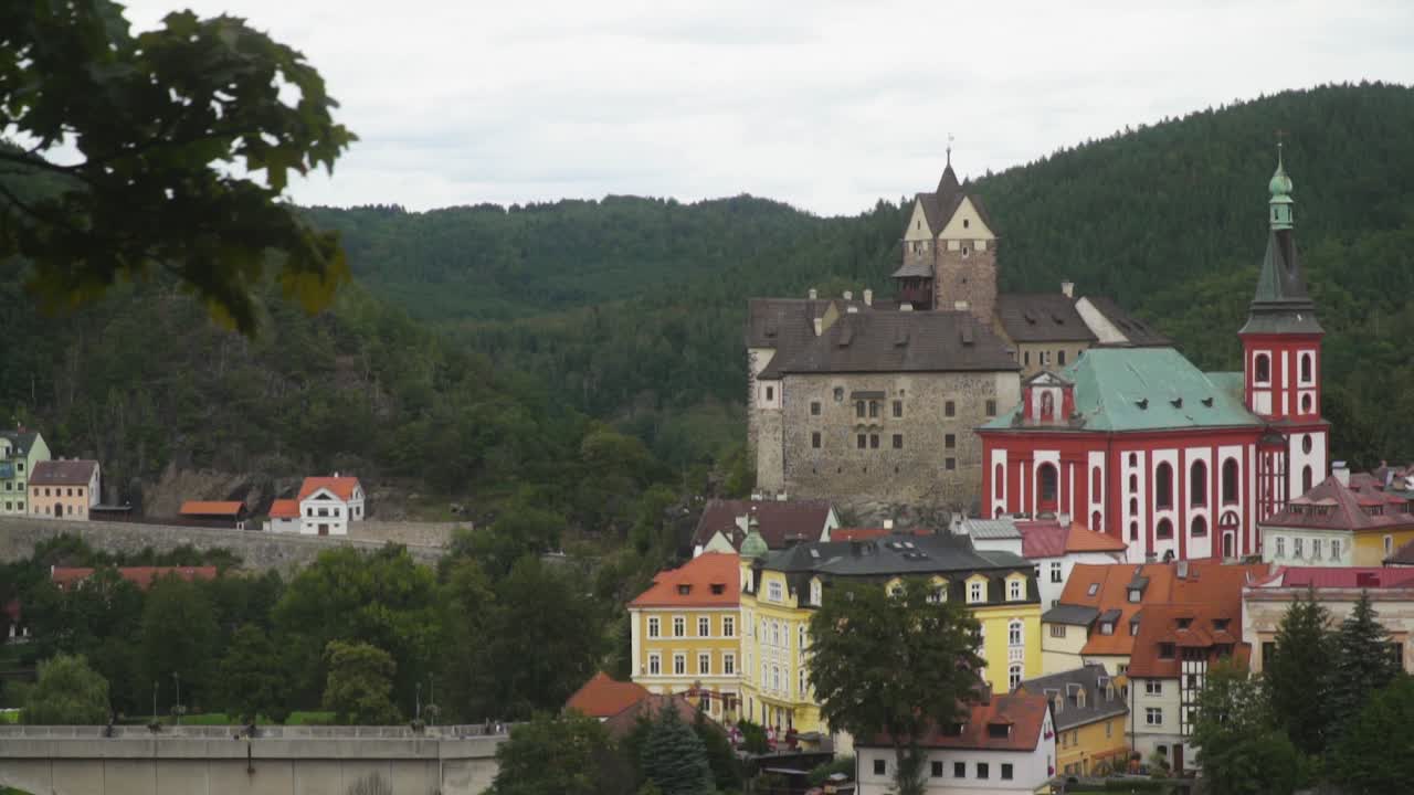 Castle Loket from a forest trail. A distant view, cloudy day