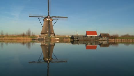 a windmill stands proudly along a canal in holland