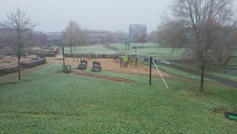 low aerial of urban basketbal court towards a children playground on a cold and misty morning