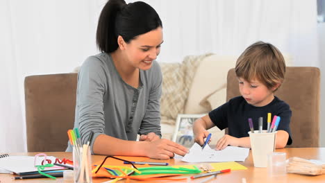 a mother smiling while her son is drawing