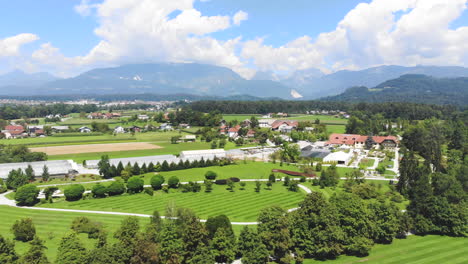 Aerial-Over-The-Volcji-Potok-Arboretum-On-A-Clear-Sunny-Day-With-Clouds-In-The-Distant