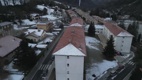 Luftdrohnen-Fliegen-über-Der-Stadt-Ribes-De-Freser-In-Girona,-Katalonien,-Spanien,-Stadtbild-Mit-Häusern-Und-Gebirgstal-Im-Hintergrund-Bei-Verschneitem-Wetter