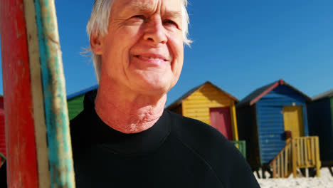 Senior-man-with-surfboard-standing-on-beach