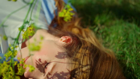 relaxed redhar woman touching face with spring flower on green grass background.