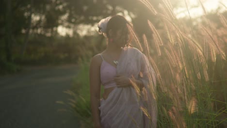 woman in pink dress enjoying golden hour in a grassy field, backlit by the sun, serene ambiance