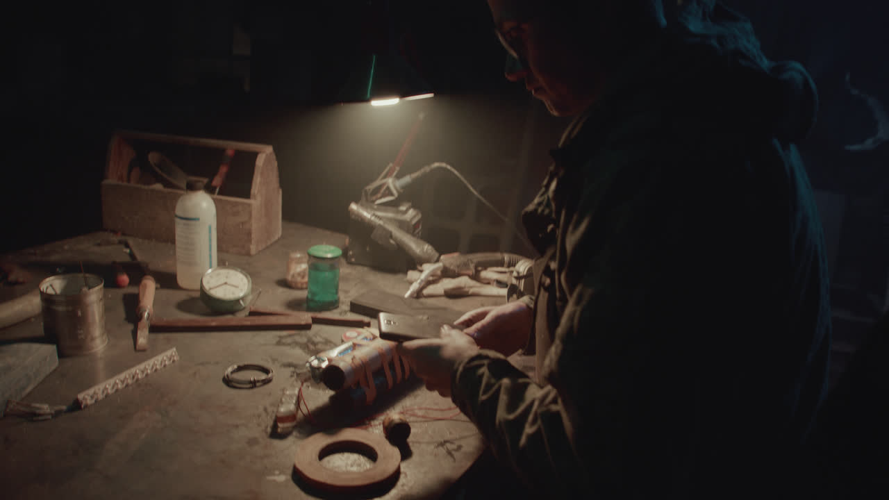 A bombmaker assembles a bomb in his workshop at night