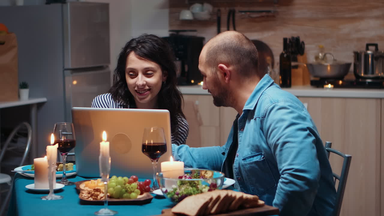 pareja usando la computadora portátil durante la cena