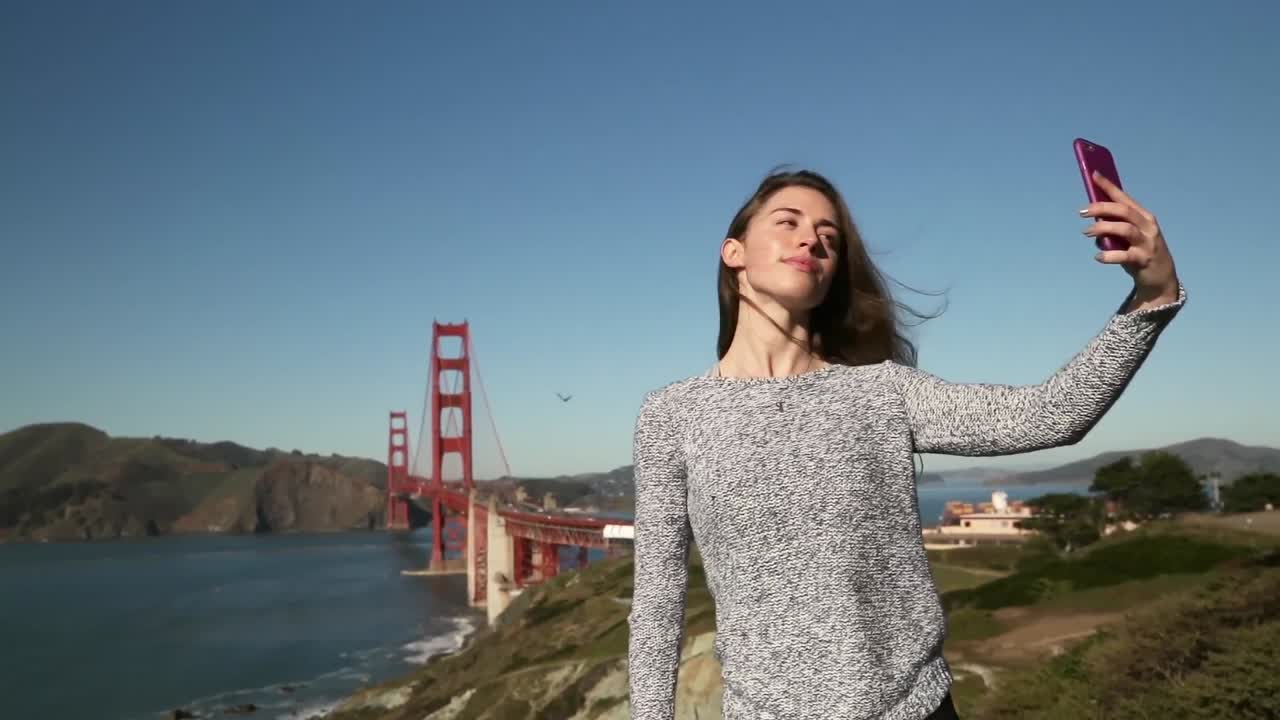 mujer tomando una selfie con el puente golden gate