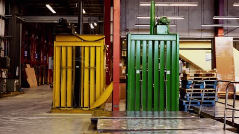 dos grandes máquinas de reciclaje de basura de cartón industrial amarillo y verde dentro de un centro de distribución de fábrica
