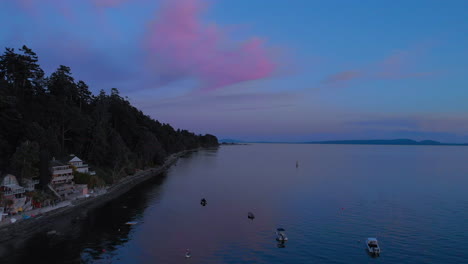 A-reversing-aerial-reaval-of-homes-on-the-shore-of-a-beautiful-beach-filling-with-parked-boats