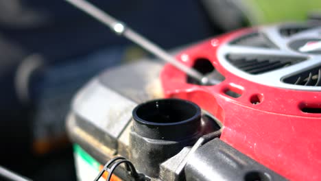la mano caucásica quita el tapón de gasolina rojo de la cortadora de césped