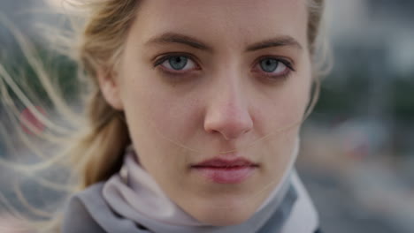 close up portrait beautiful blonde woman turns head looking serious at camera in city wind blowing hair independent caucasian female slow motion feminine beauty