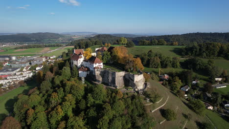 maravillosa toma aérea en órbita y a media distancia en un día soleado del castillo de lenzburg y donde se puede ver la bandera suiza