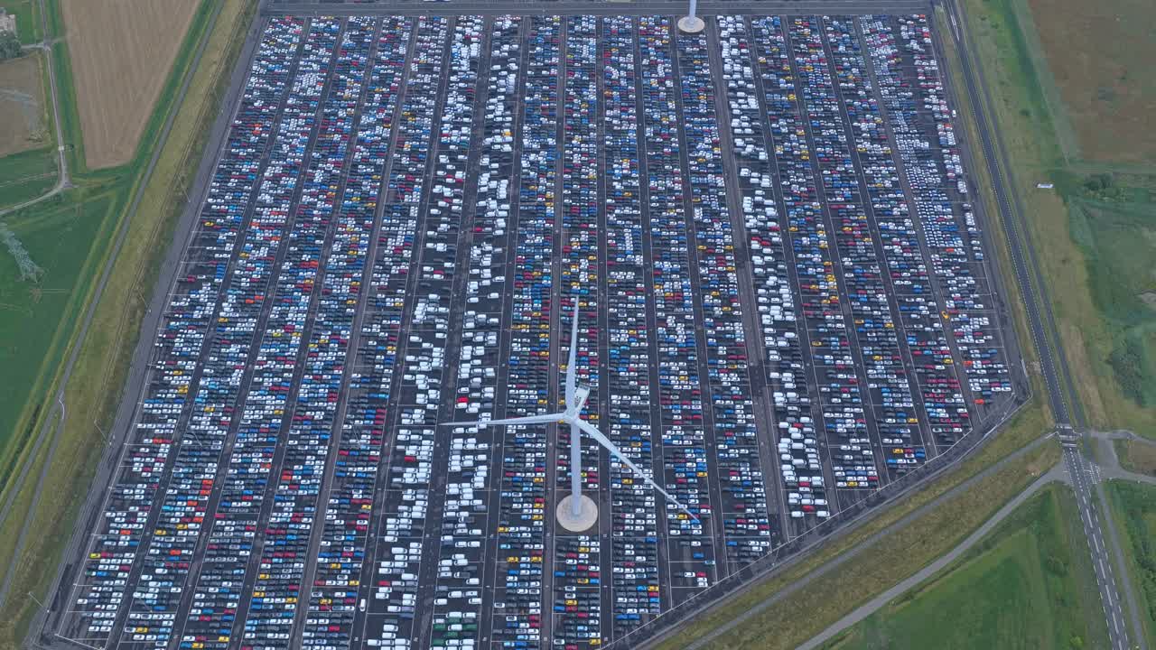 Globaler Autologistik-Standort mit geparkten Fahrzeugen und sich drehendem Windrad