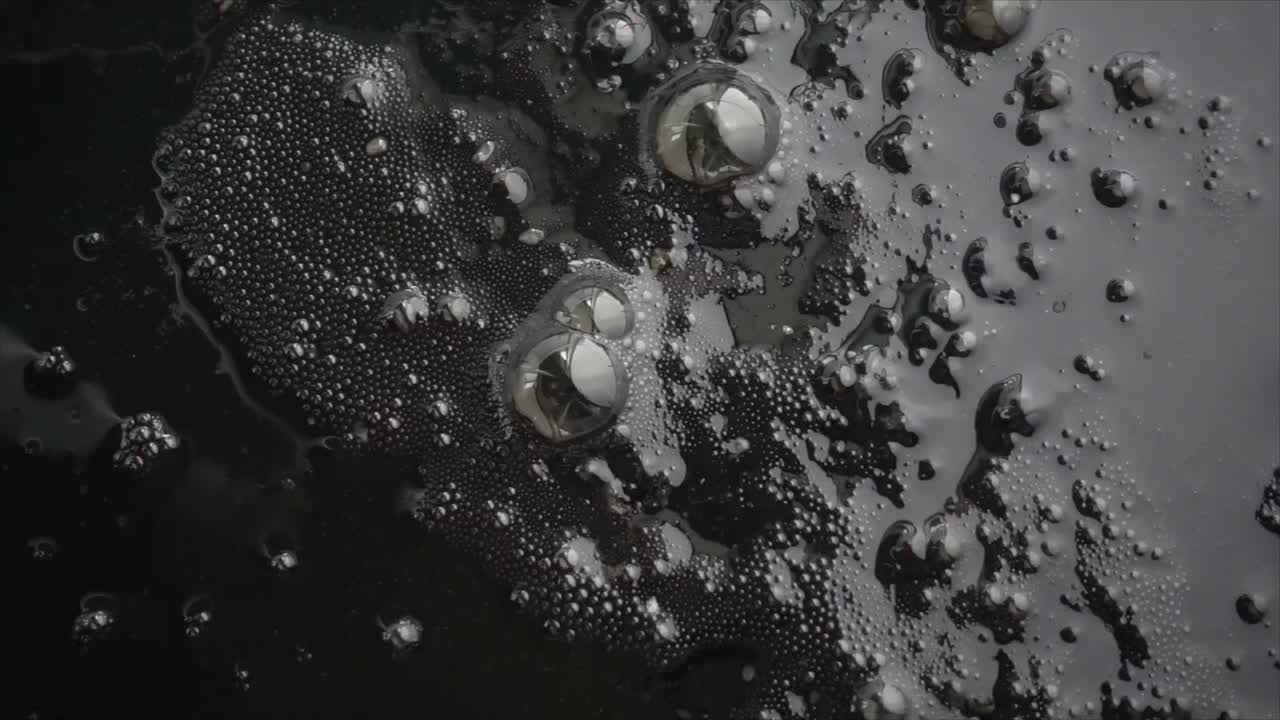 Vista astratta di bolle su una superficie scura e oleosa
