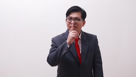 asian businessman standing while showing silence gesture