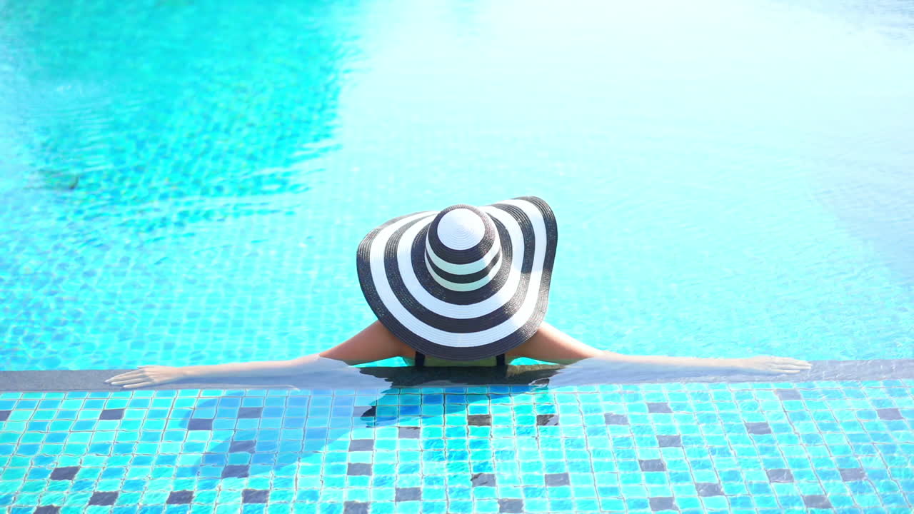 Glamouröse Frau mit Sommerhut im Schwimmbad, Modekonzept, Zeitlupe