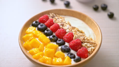 homemade yoghurt bowl with raspberry, blueberry, mango and granola - healthy food style