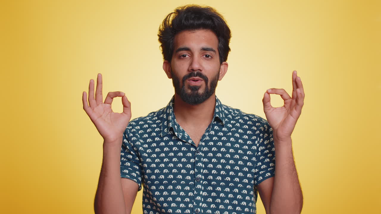 Young indian man breathes deeply eyes closed meditating with concentrated thoughts peaceful mind