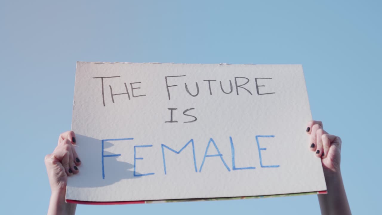 Hands Holding 'The Future Is Female' Protest Sign Against Blue Sky