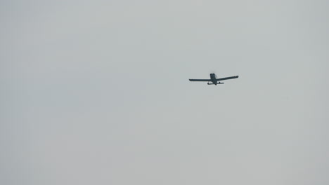 light aircraft approaching directly with visible landing gear and propeller against overcast sky