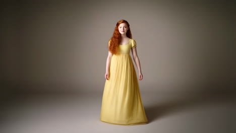 a woman with red hair in a yellow period dress standing in a studio