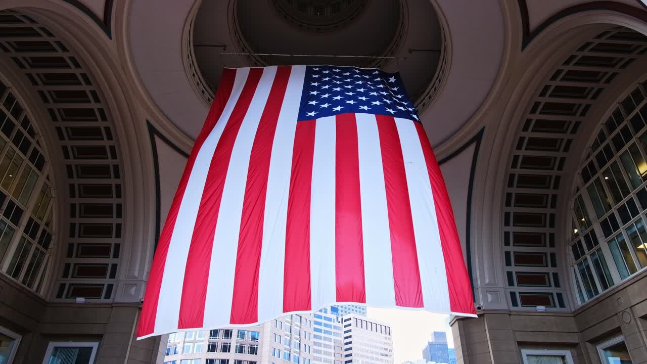 American flag is blown in Rowes Wharf in daylight. Bottom view. Tall buildings in background. Boston, Massachusetts, USA