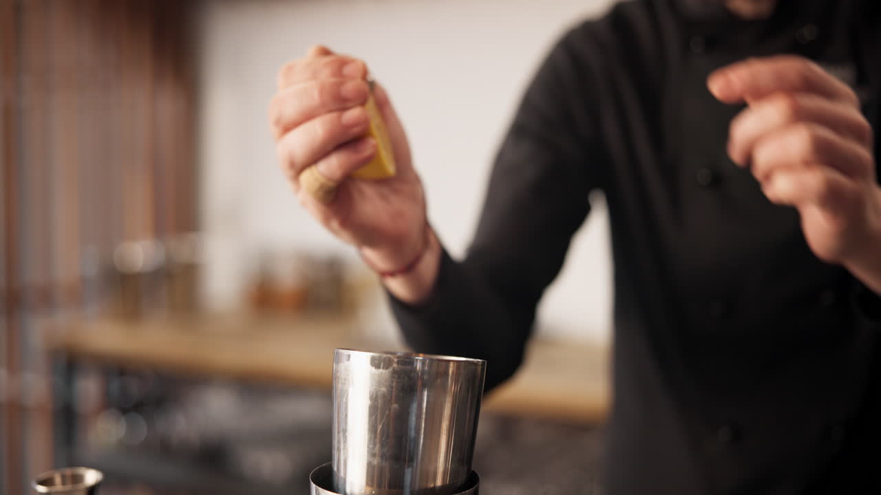 바텐더가 레몬을 지거로 압축하고 있습니다.