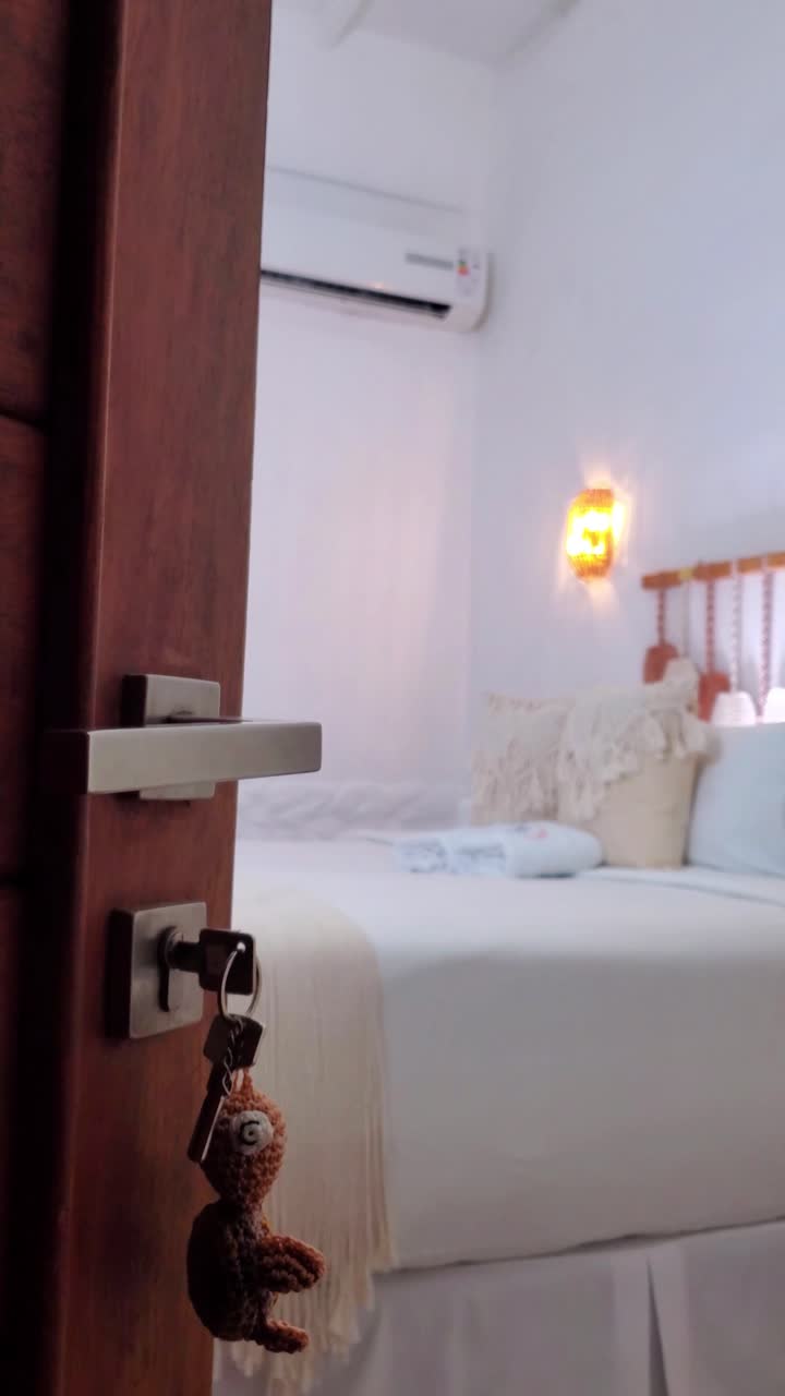 Modern, clean bedroom viewed from an open wooden door. Hospitality Concept
