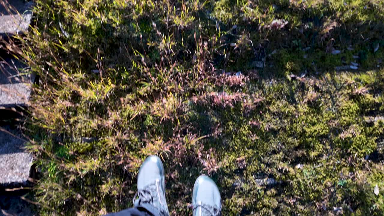 First person view of hiker legs riding chair lift over grass and moss, enjoying pov perspective