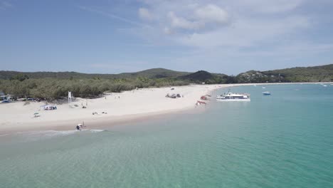 tourists and tourist boats at pristine beach in great keppel island, queensland during summer