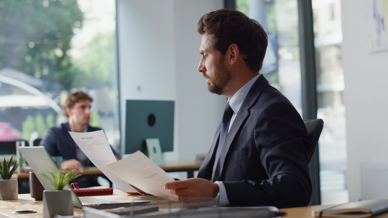 Serious businessman working laptop reading report in office workspace closeup