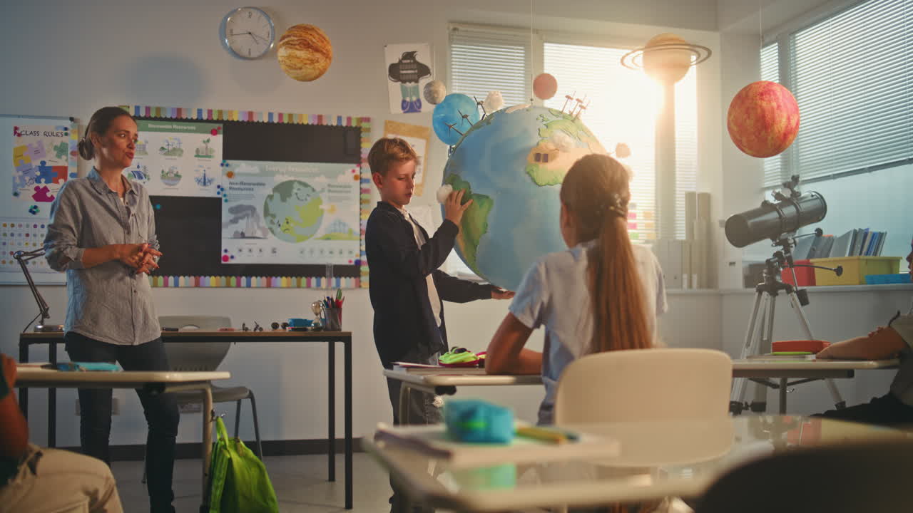 Primary School Boy Presenting Green Energy Sources in Front of Class Using Earth Model