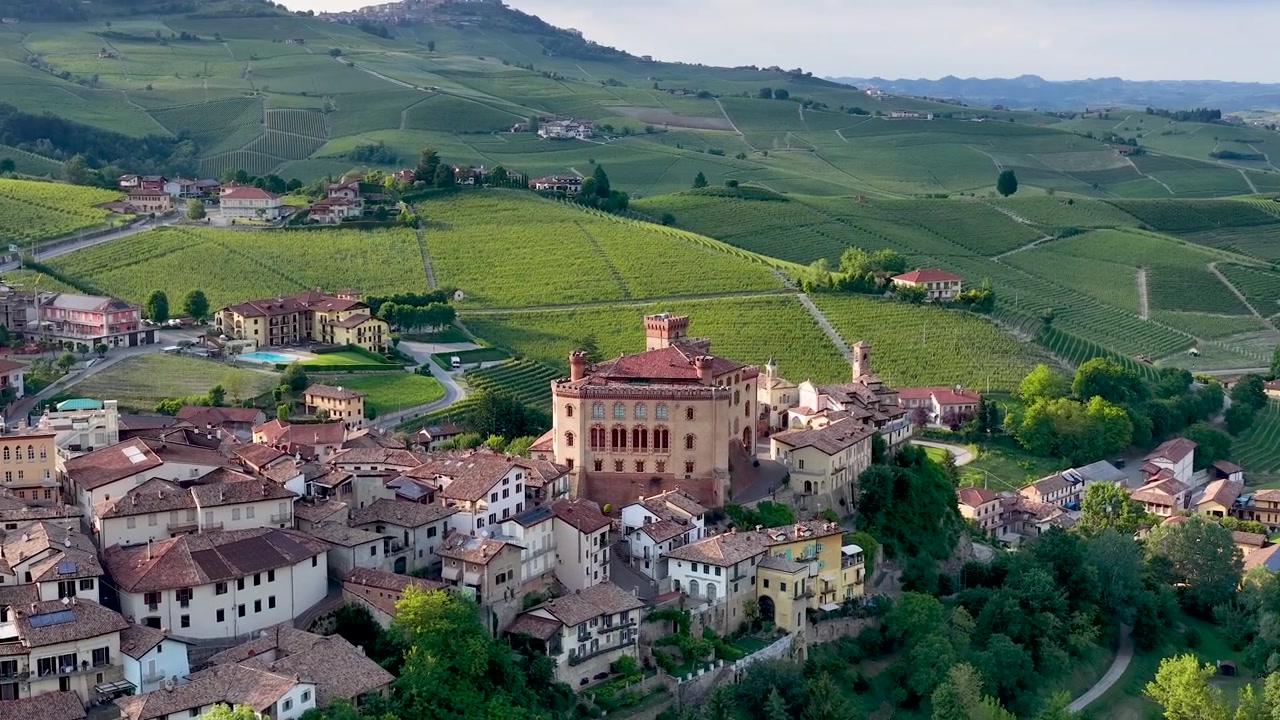 Drone sorvola rigogliosi vigneti verdi e un borgo storico in Piemonte, Italia