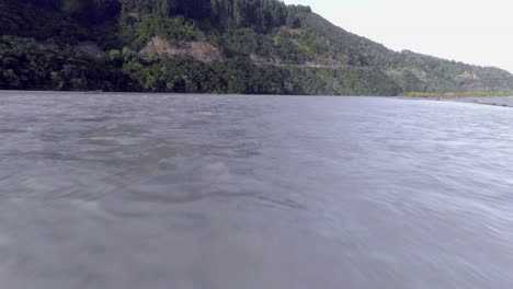 drone volando cerca de la playa de rocas y sobre aguas turbulentas en el río, antena