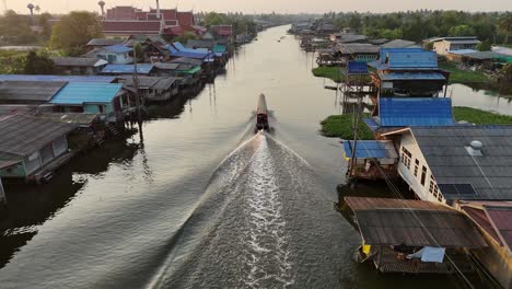 a longtail boat gliding through a watery canal outside of bangkok in the pak kret neightborhood