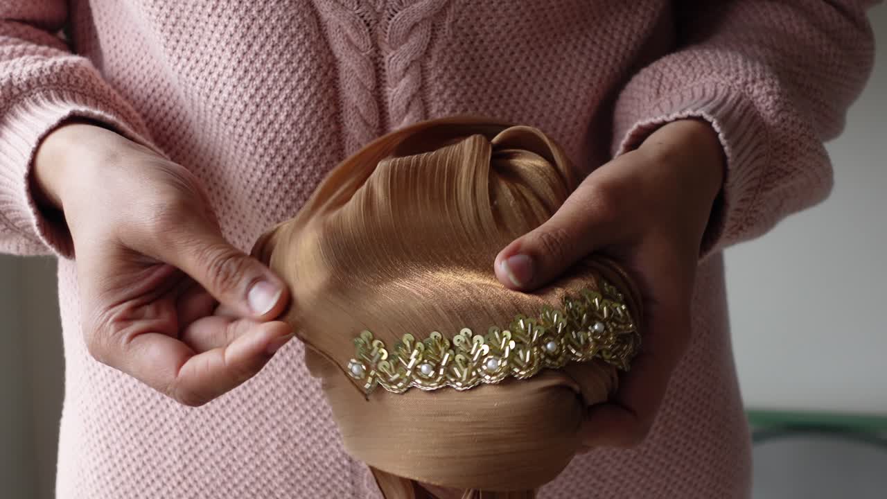 Woman's Hands Folding Gold Embellished Fabric with Sequins and Pearls