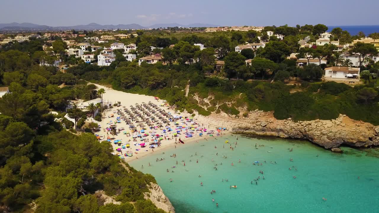 Panoramica da sinistra a destra dell'inquadratura di fronte alla spiaggia appartata di Cala Anguila, una splendida località turistica nell'isola di Maiorca in Spagna.