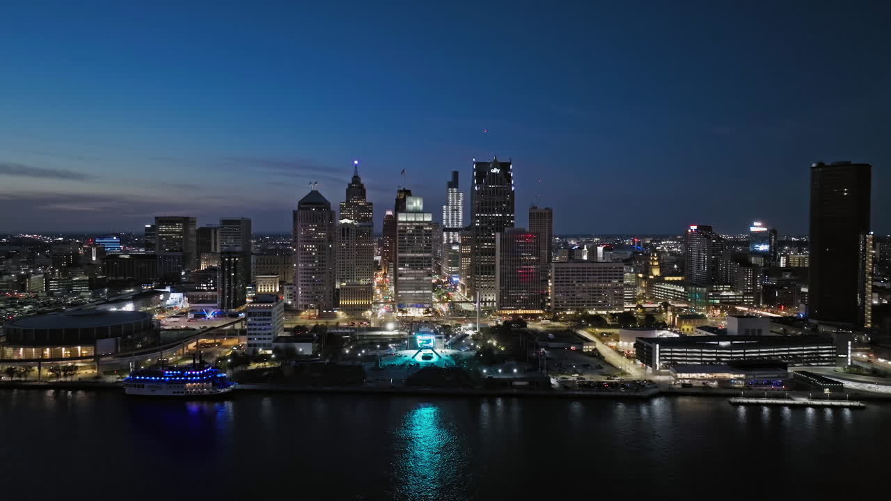 Aerial tracking shot in front of the illuminated downtown Detroit, dusk in USA