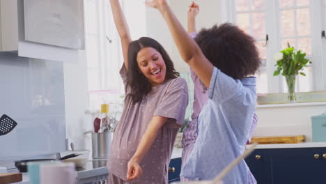 Familia-Embarazada-Con-Dos-Mamás-Bailando-Haciendo-Panqueques-Matutinos-En-La-Cocina-Con-Su-Hija