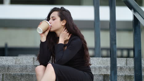 closeup woman sitting on stairs outdoors. woman touching hair on stairs outside