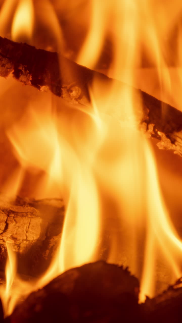 Un primo piano di fiamme di un fuoco di legna che brucia in un camino, in verticale