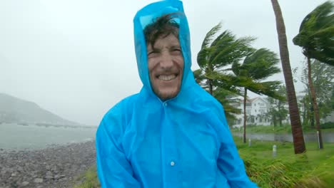 a man in a raincoat is under a hevy rain and stormy wind. shot on an action camera. tropical storm concept. contains natural sound