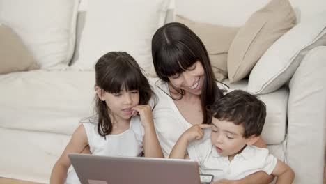 madre y dos hijos usando una aplicación de aprendizaje en la computadora portátil