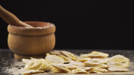 tasty raw ravioli with flour and basil on wood table