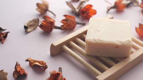jabón hecho a mano en un plato de jabón de madera con flores secas